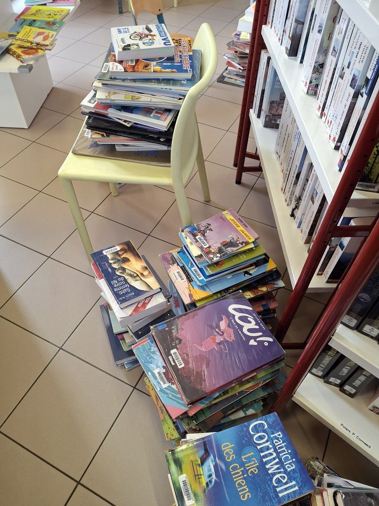 Des livres sont triés et mis en tas sur le sol d'une bibliothèque