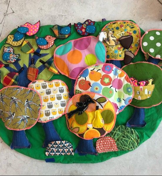un petit tapis au sol, sur lequel sont accrochés des arbres et divers éléments de la forêt : oiseaux, fruits, animaux...
